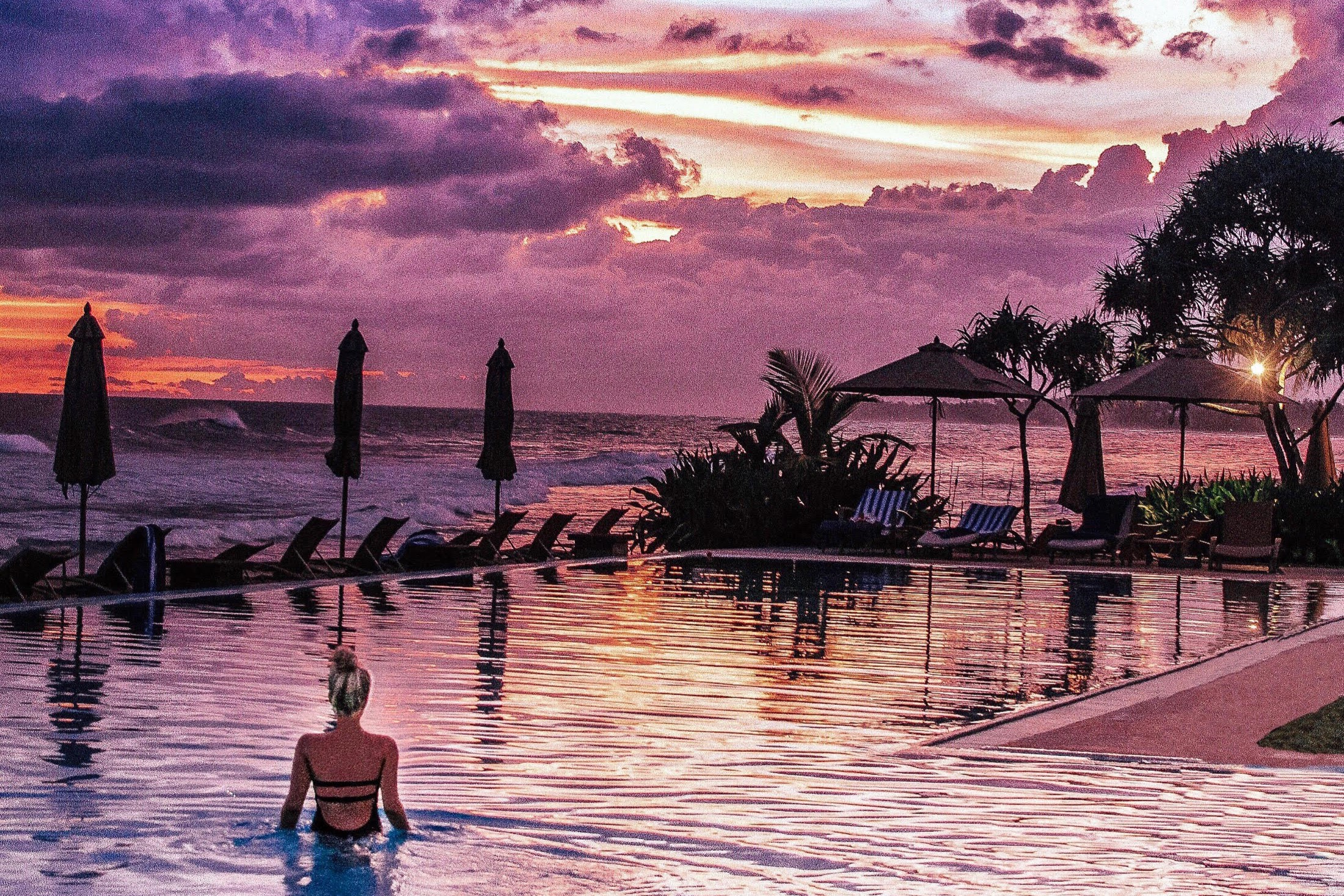 Lady watching a tropical, vibrant sunset and relaxing in the infinity pool at The Fortress, one of the best boutique hotels in galle